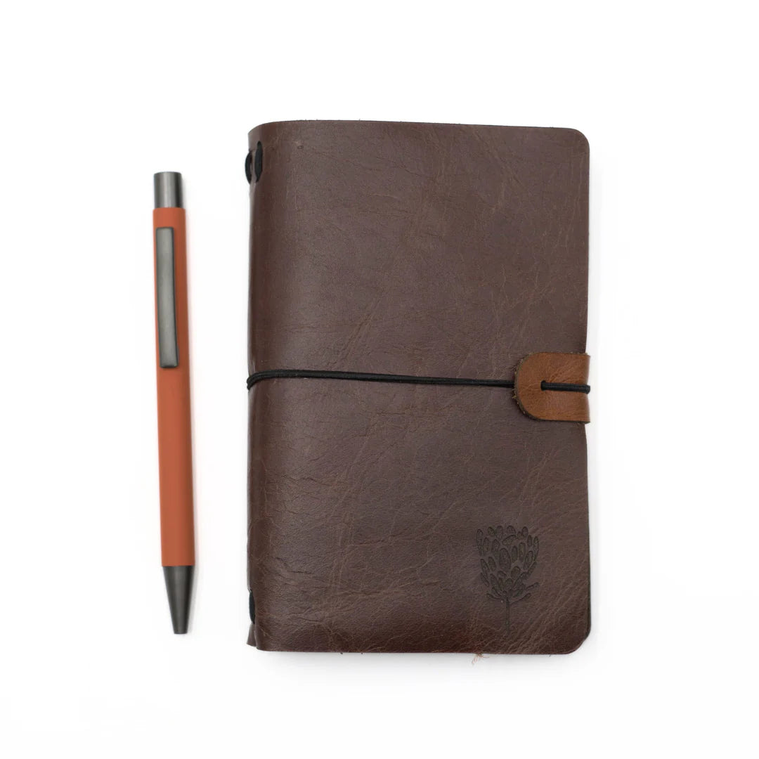 Brown leather A6 notebook with a pen on a white background
