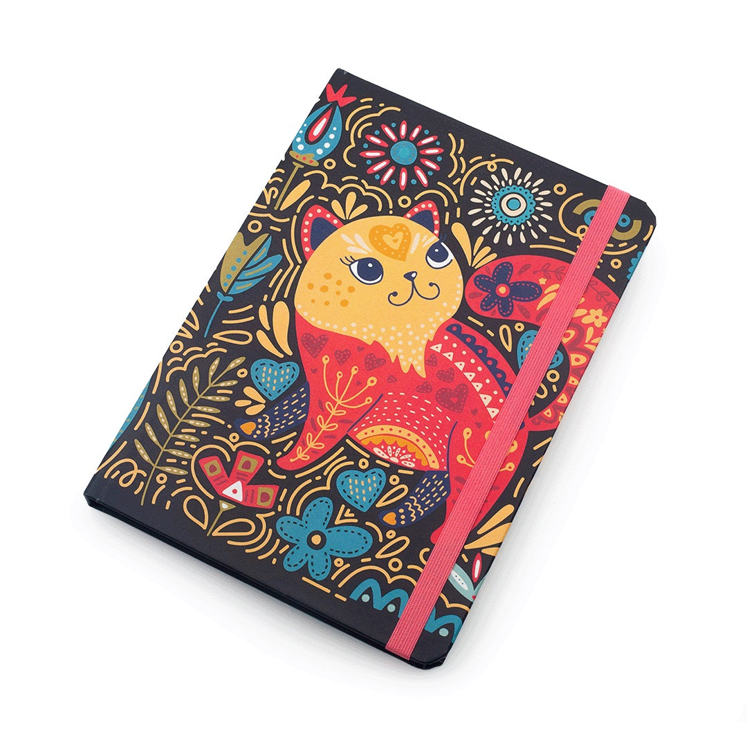 A hardcover notebook with a colorful folk-art style cat illustration on a black cover, featuring a pink elastic closure band, photographed on a clean white background.