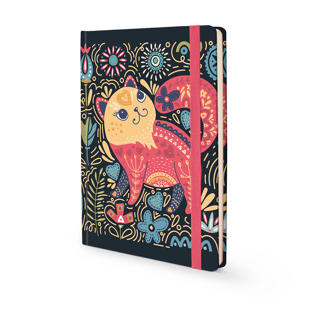A hardcover notebook with a dark navy cover decorated with a colorful folk-art style cat illustration. The notebook has a pink elastic closure band and is shown at an angle on a clean white background.