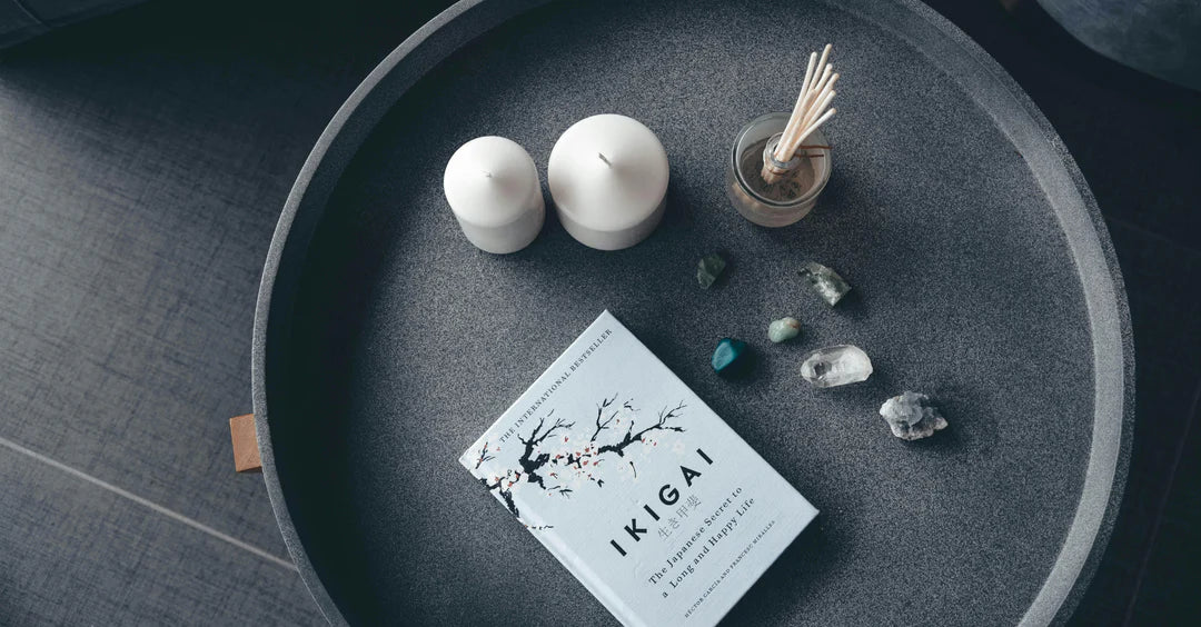 Japanese international bestseller Book titled 'IKIGAI' on a dark surface with candles and stones