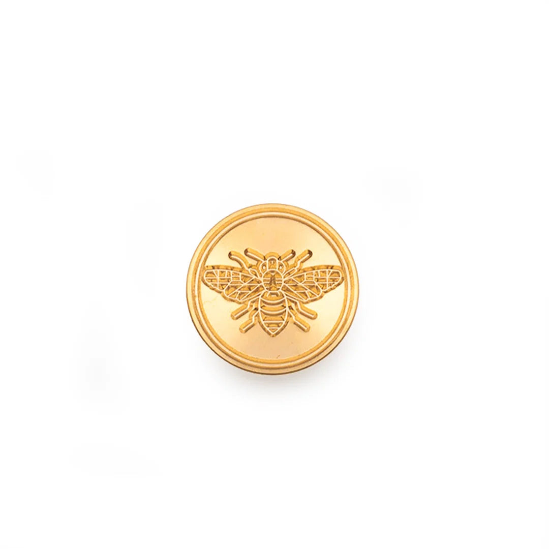 A round gold stamp-seal featuring an embossed bee design in the center, set against a plain white background.