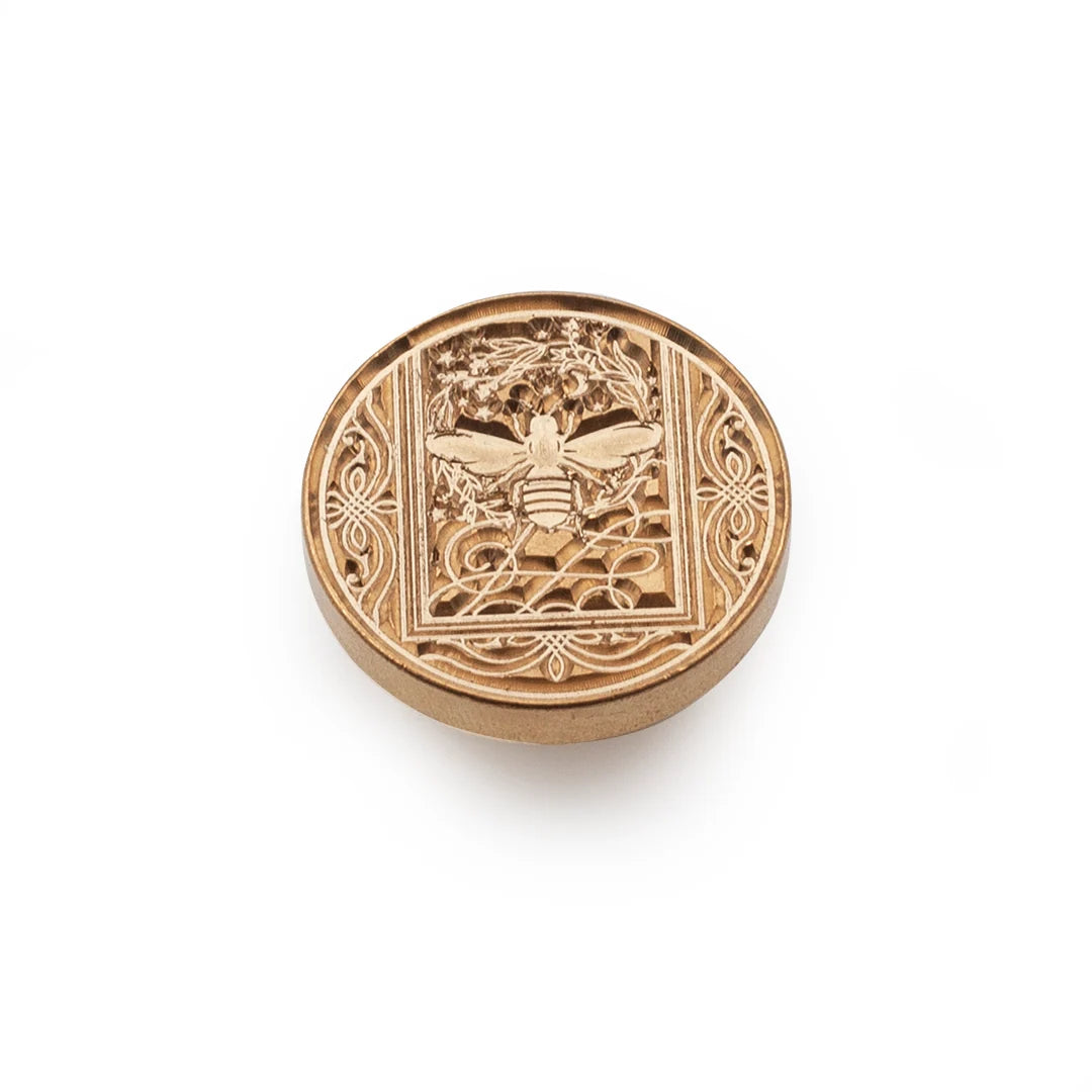 A round, bronze-colored metal stamp-seal featuring an embossed bee and floral scrollwork design, shown on a clean white background.
