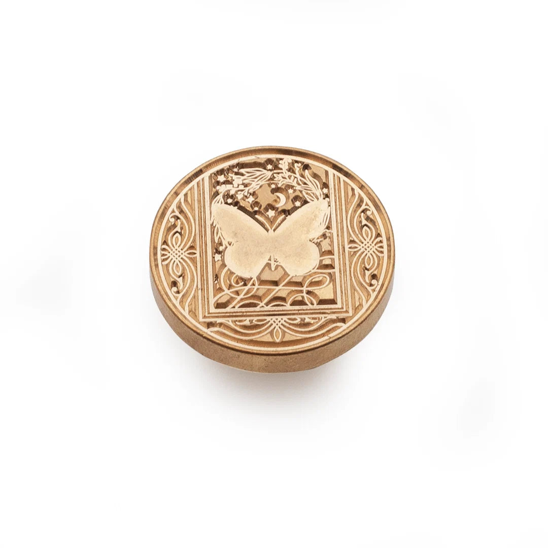 A round, metallic gold stamp-seal featuring an embossed butterfly design and ornate scrollwork, set against a plain white background.
