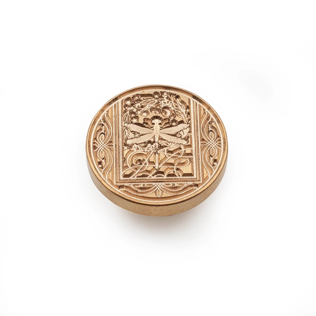 A round bronze stamp-seal with an embossed dragonfly design in the center, set against a plain white background.