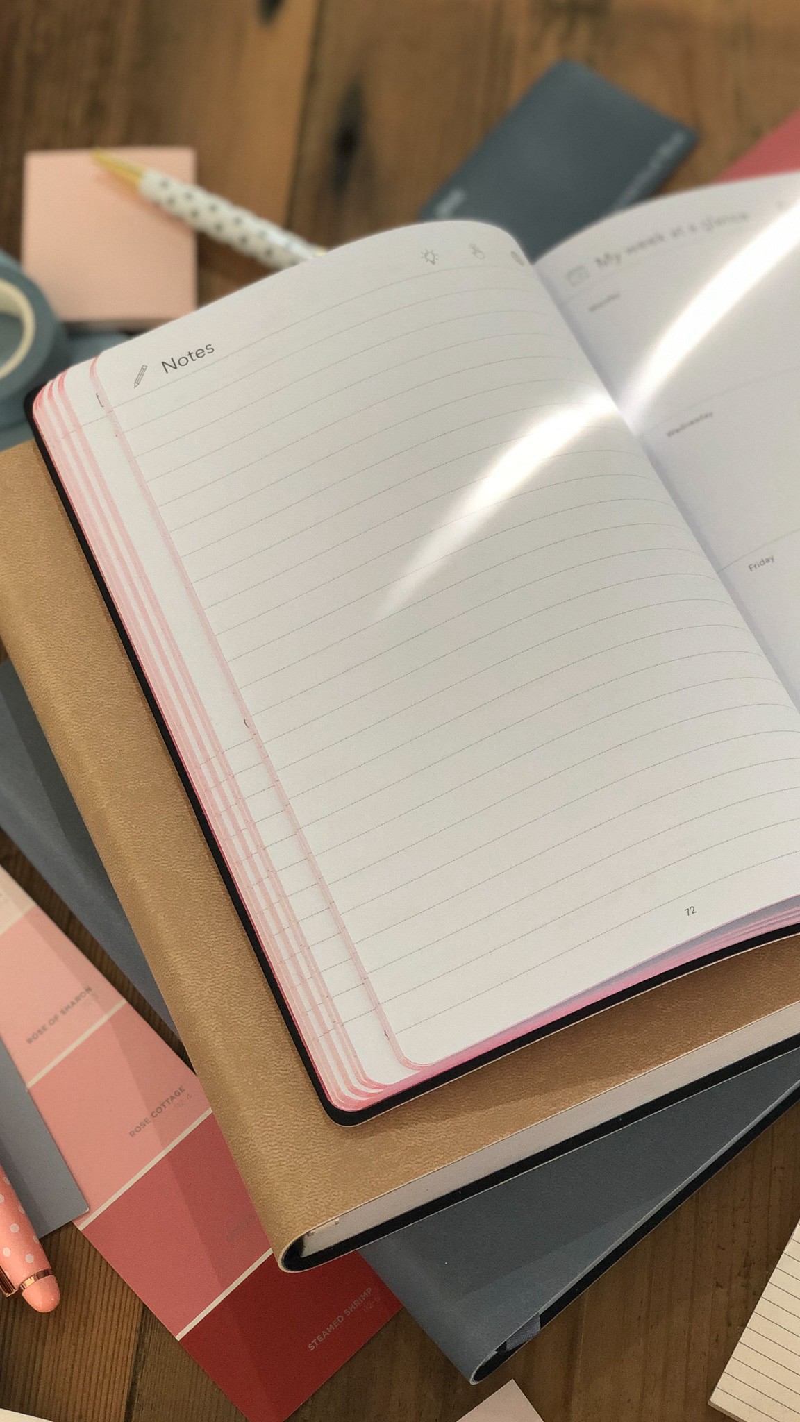 Stack of multi planners with a notes pages to write in on a wooden surface