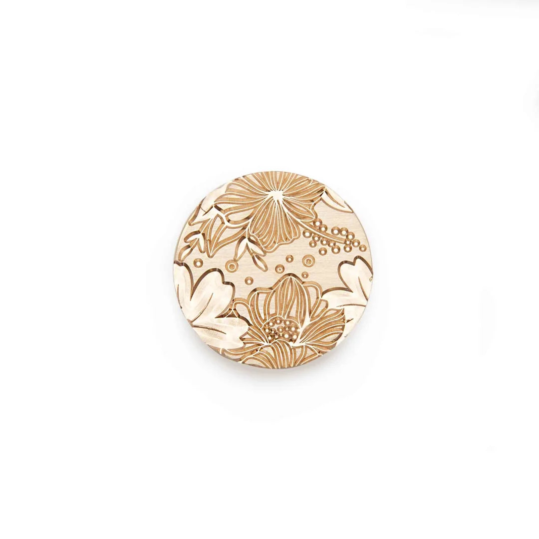 A round wooden stamp-seal-engraved floral pattern in a warm tan color on a light natural wood base, centered on a plain white background.