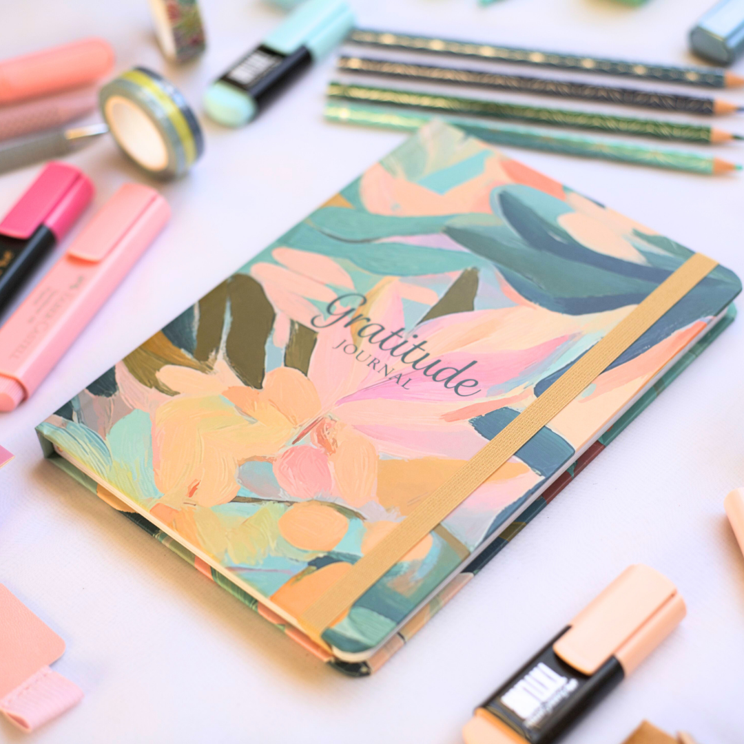 Floral 'Gratitude Journal' on a white surface with stationery items.