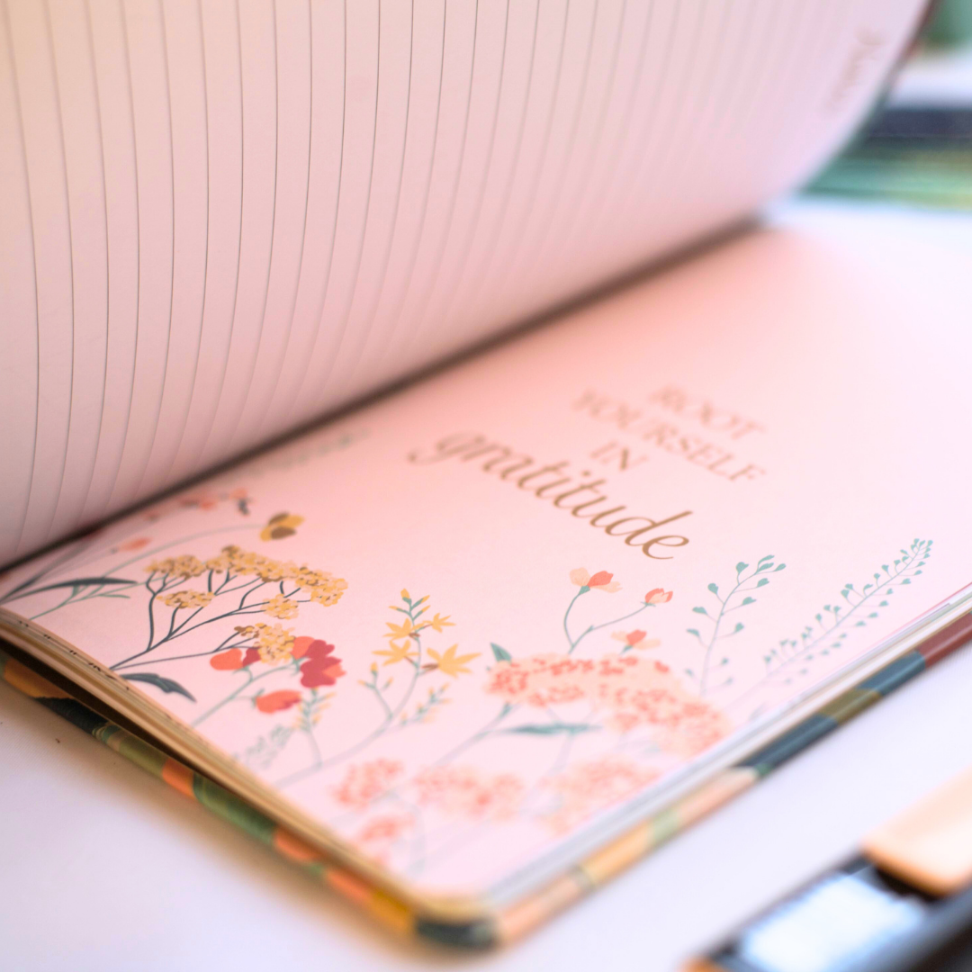 Open journal with floral design and 'gratitude' text on a light background