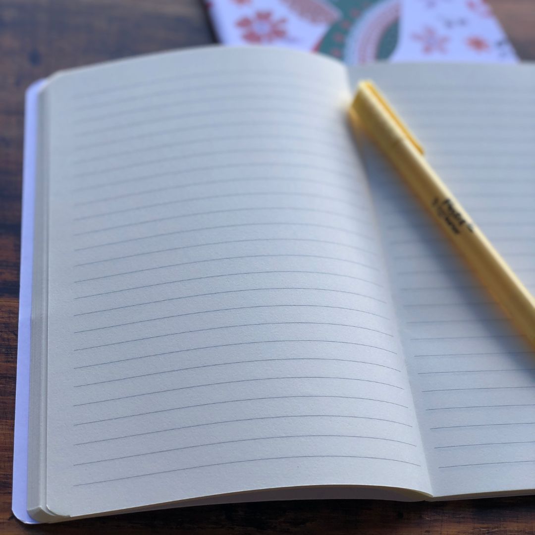 Open notebook with lined pages and a yellow pen on a wooden surface