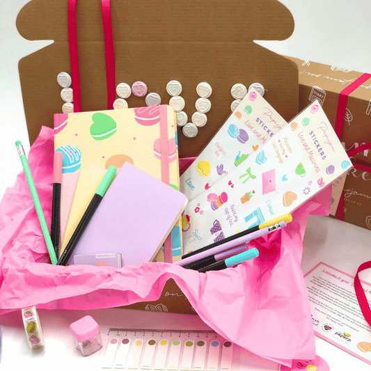 Love and Macaron Gift Box with Stationery pastel themed items including notebooks, pens, and stickers in a decorative box with pink ribbon.