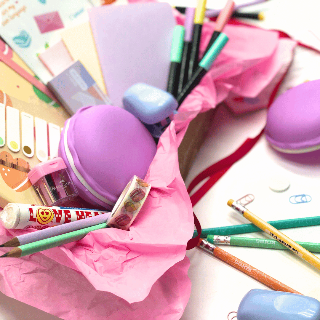 Love and Macaron Gift Box has an assortment of stationery items including pencils, erasers, pens, stickers, pencils and loads more goodies in the box on a white background.