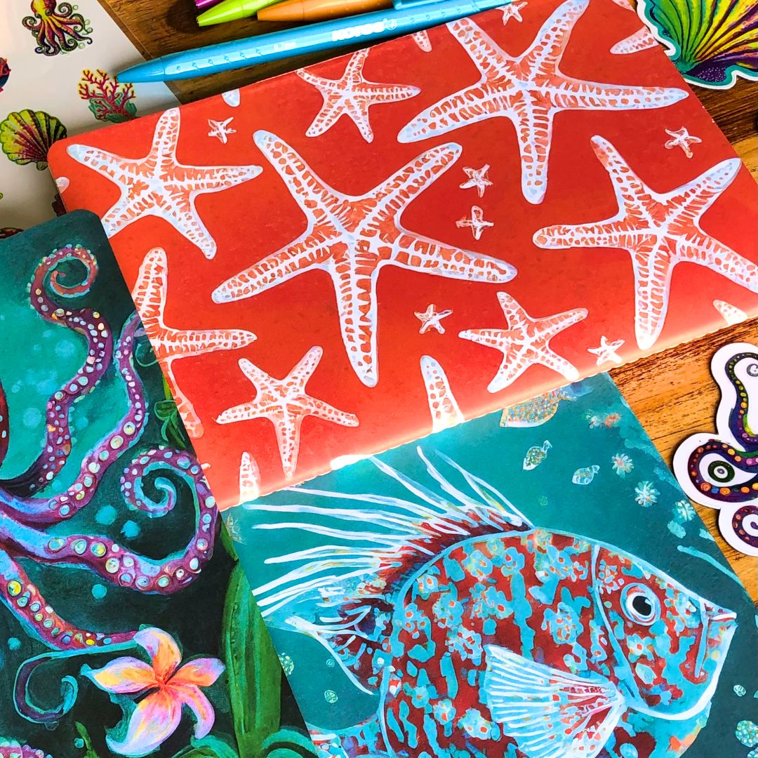 Ocean Treasures Gift box has colorful stationery items including a red notebook with starfish pattern, a green notebook with octopus design, and a blue notebook with fish design.