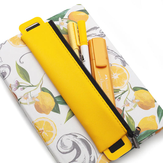 Yellow pencil pouch case with a floral and lemon pattern on top of a journal with highlighters and pens inside pouch on a white background