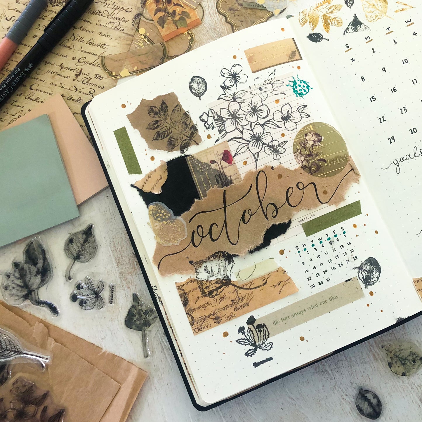Decorative Junk Journal with 'October' theme on a textured surface with stationery items.