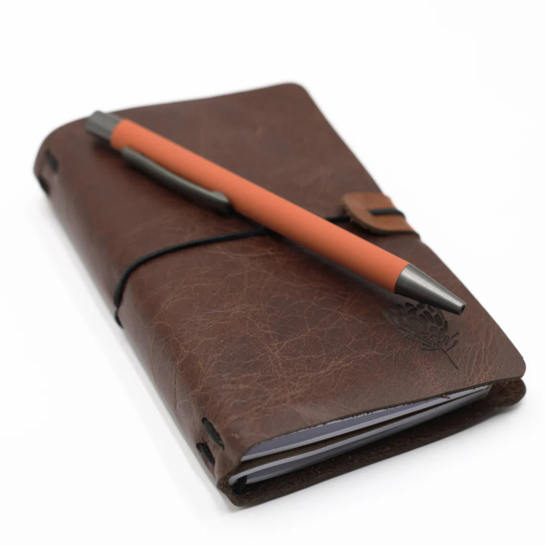 Brown leather notebook with an orange pen on a white background