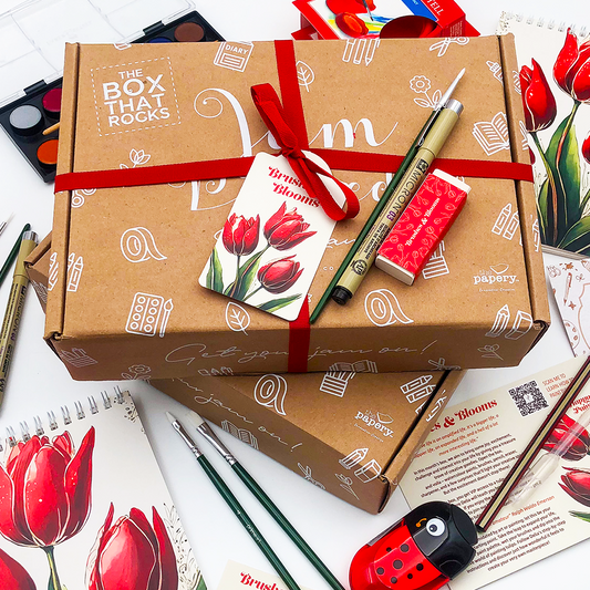 Brushes & Blooms gift Box that rocks with stationery items and red ribbons on a white background