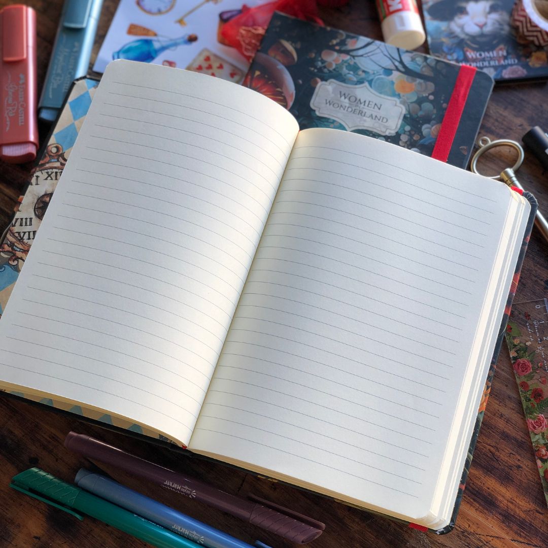 Open Retro Women in Wonderland Journal with lined pages on a wooden surface with stationery items.